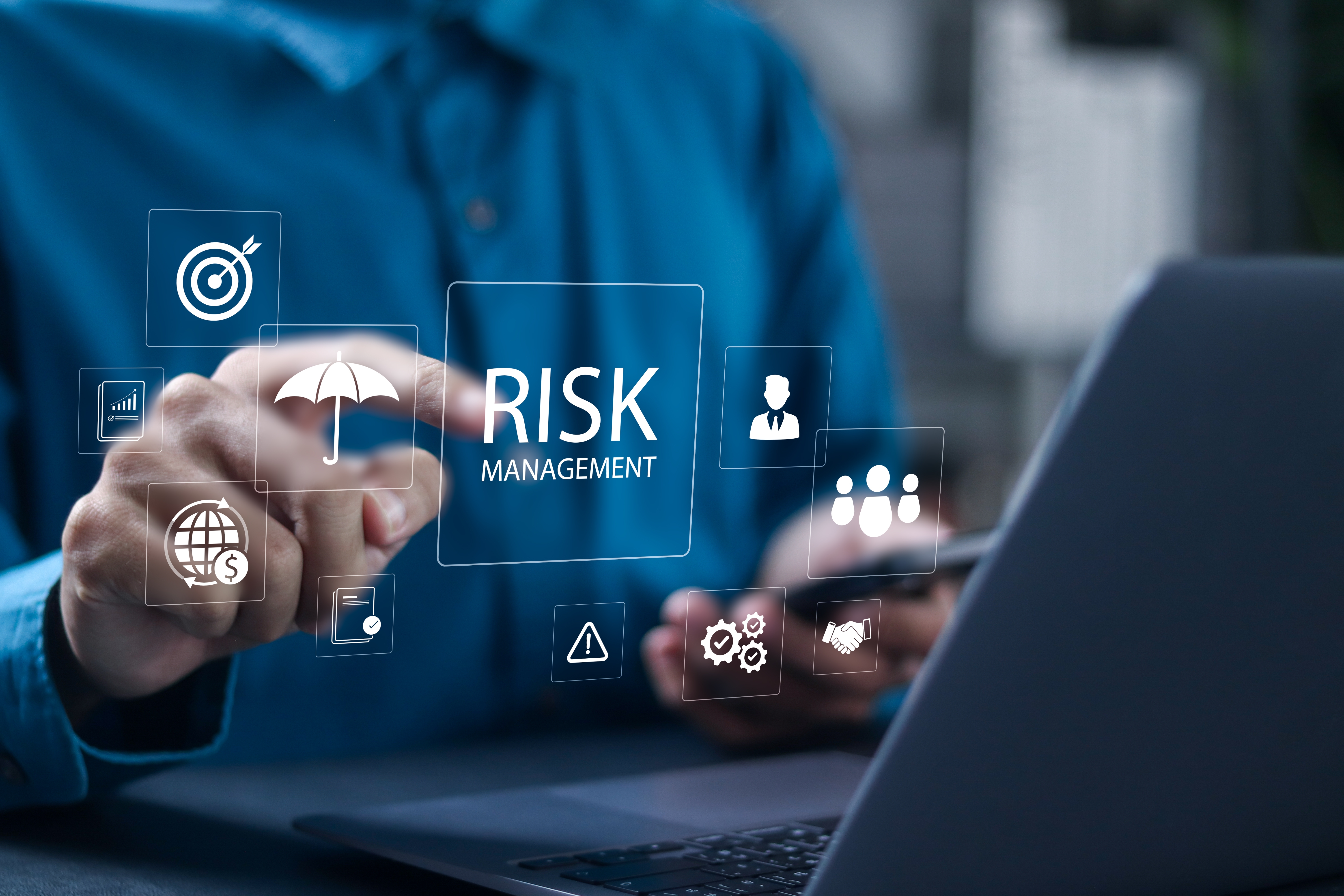 Man sat in front of a laptop with floating images in front showing that he is working on anti money laundering risk management